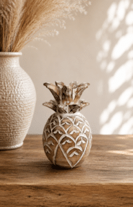 Ananas décoratif en bois sculpté blanchi posé sur une console en bois dans une décoration bohème