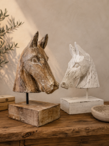Deux bustes de cheval en bois sculpté, naturel et blanchi, présentés sur une console dans une ambiance bohème chic.