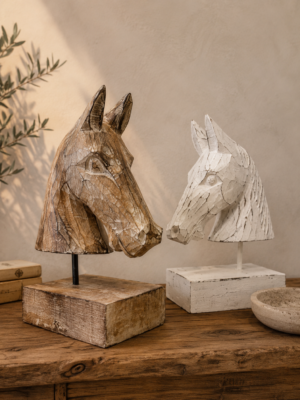 Deux bustes de cheval en bois sculpté, naturel et blanchi, présentés sur une console dans une ambiance bohème chic.
