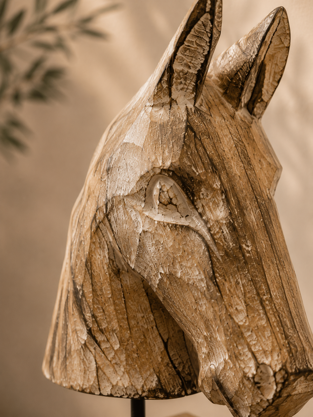 Gros plan sur les détails de sculpture et le veinage d'un buste de cheval en bois.