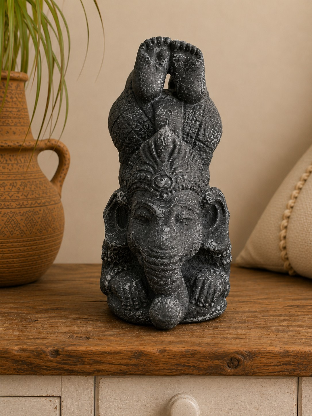 Statue Ganesh en béton noir patiné en position yoga sur une console en bois dans une décoration bohème et zen.