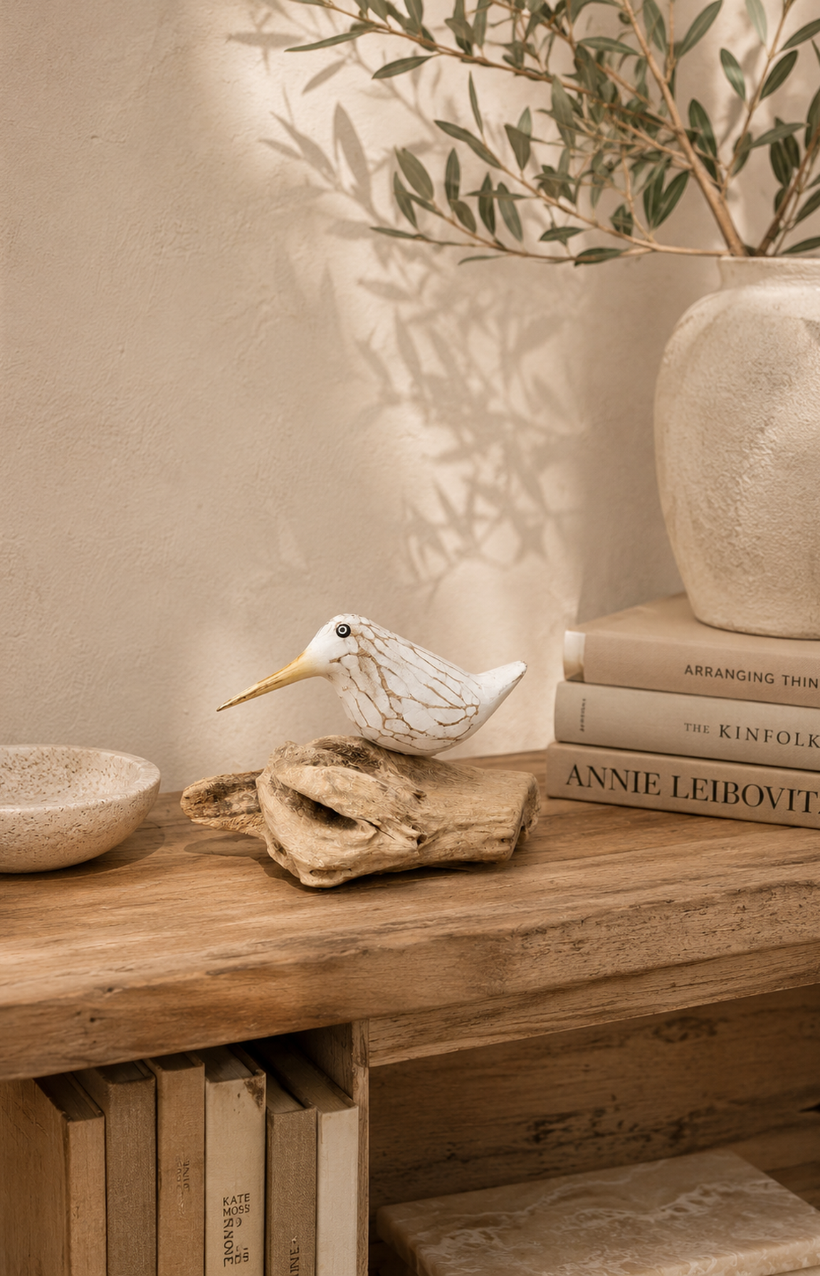 Oiseau décoratif en bois sculpté présenté sur une bibliothèque aux tons naturels.