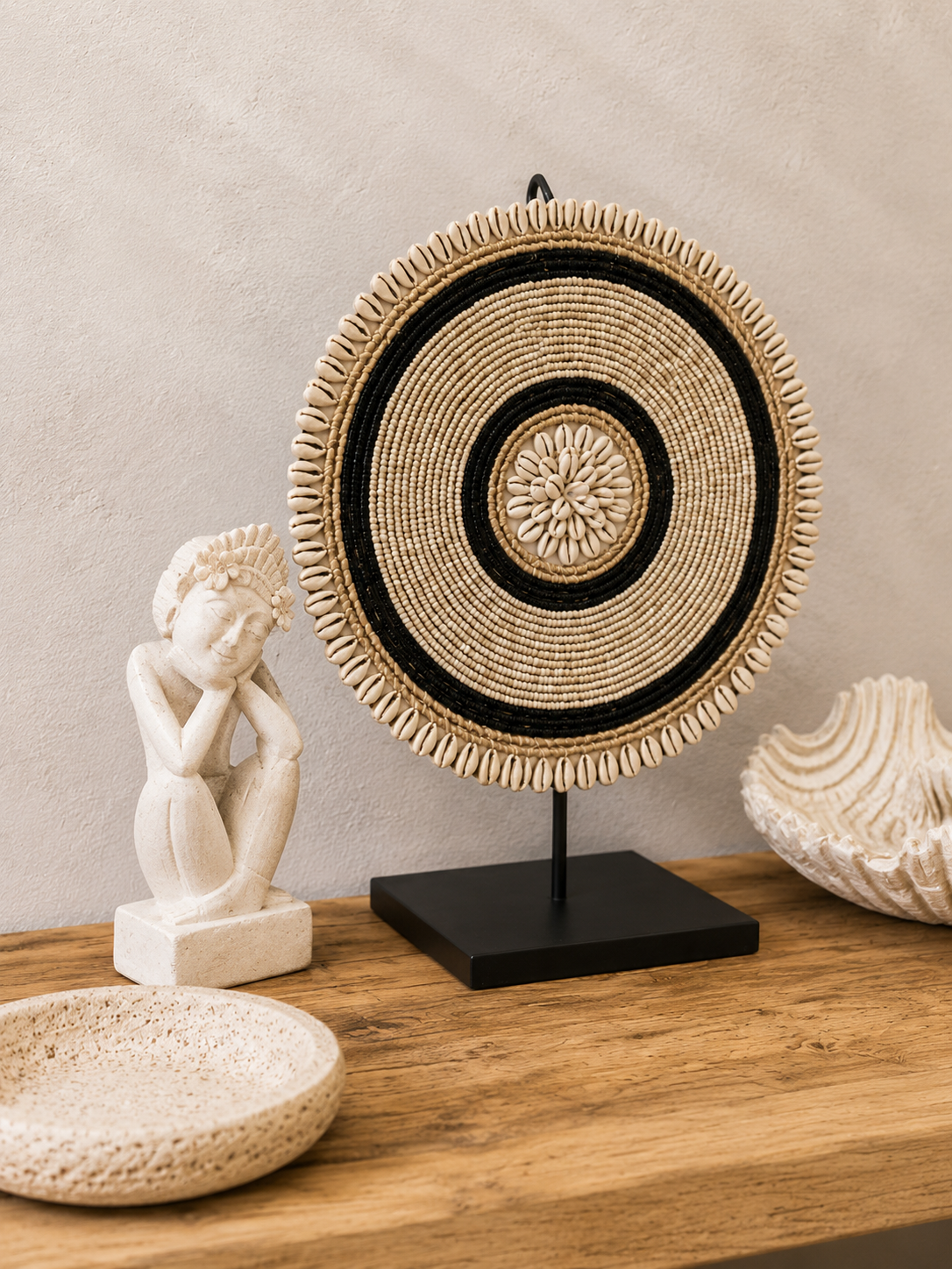 Décoration artisanale en perles beige et noires présentée sur une console en bois naturel.