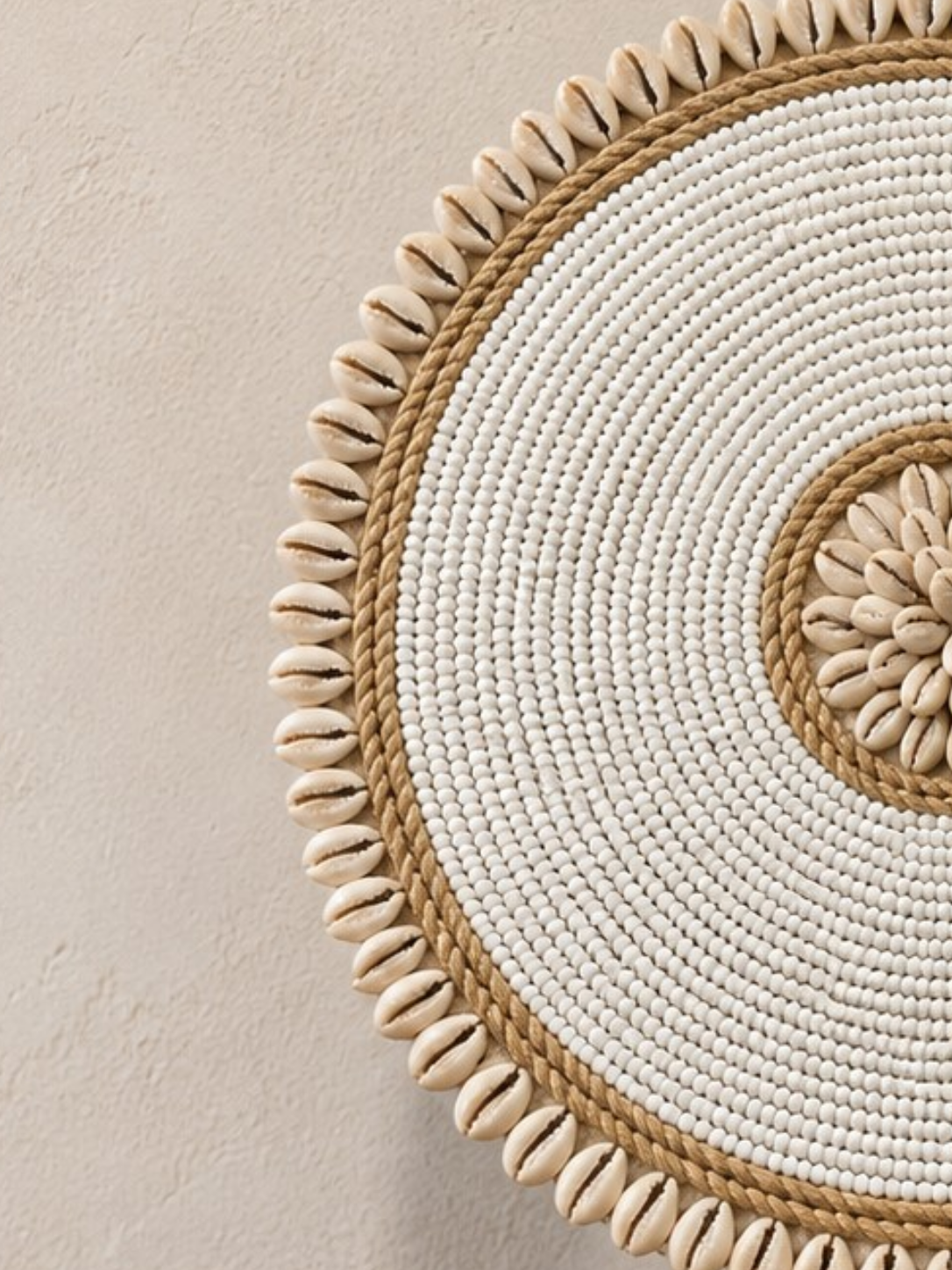 Gros plan sur les perles blanches, la corde naturelle et la rosace centrale en coquillages cauris.