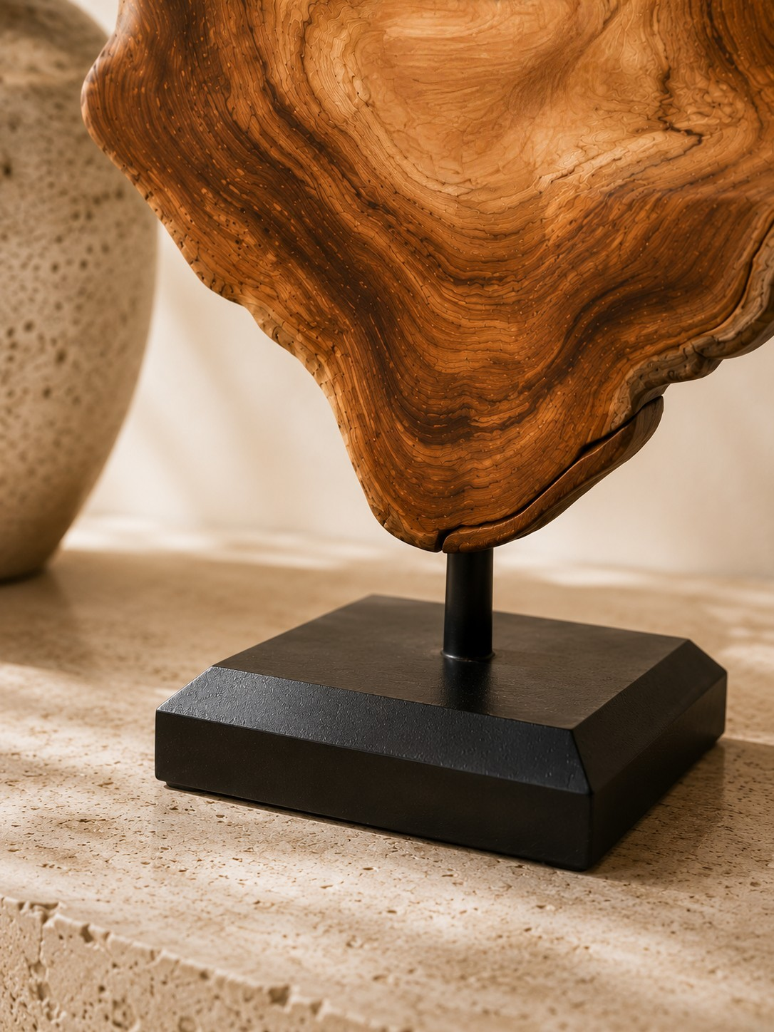 Détail du socle noir contrastant avec les nuances chaleureuses du bois.
