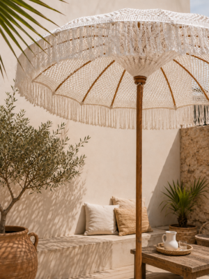 Parasol en macramé blanc à franges installé sur une terrasse bohème chic avec décoration méditerranéenne
