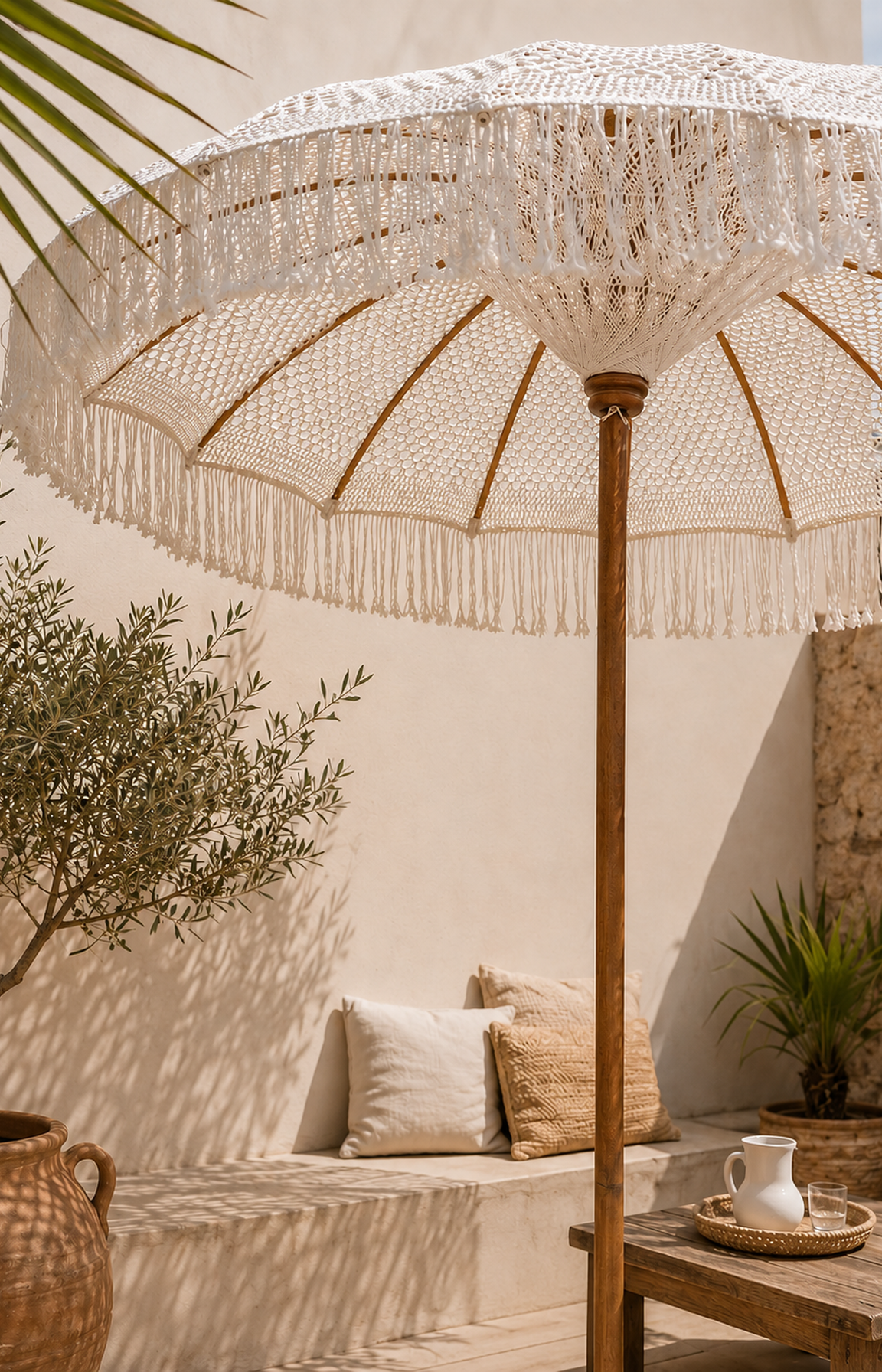 Parasol en macramé blanc à franges installé sur une terrasse bohème chic avec décoration méditerranéenne