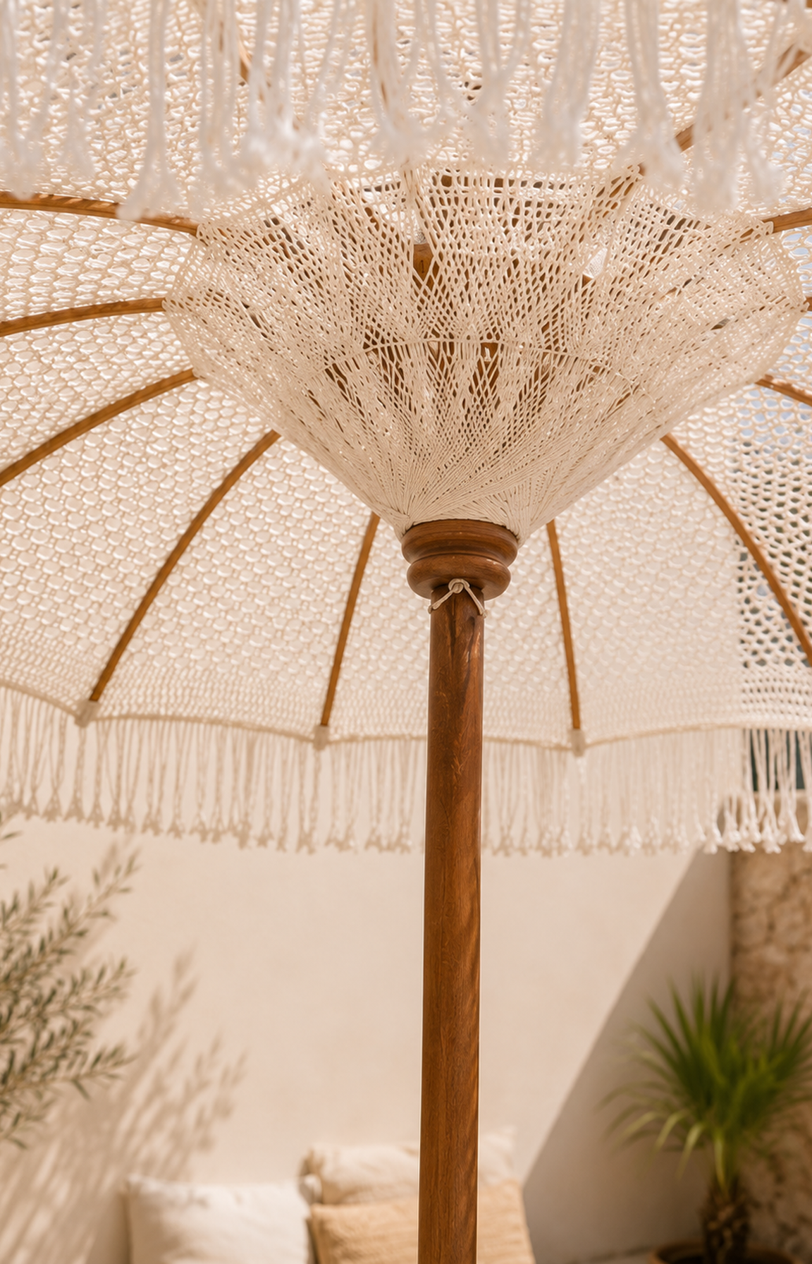 Détail du tissage intérieur d'un parasol en macramé blanc avec franges et structure en bois