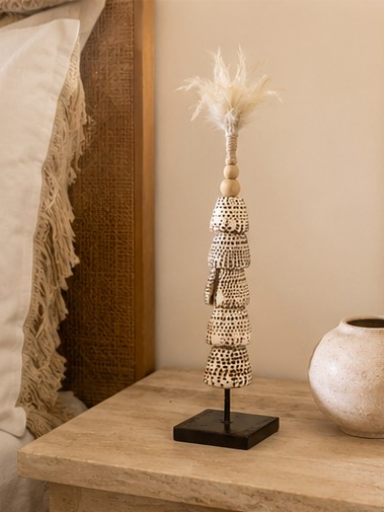 Totem décoratif en coquillages naturels et plumes présenté dans une ambiance bohème chic.