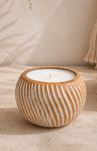 Grande bougie en bois massif sculpté avec rainures blanches et mèche centrale, présentée dans une décoration bohème minimaliste aux tons naturels.