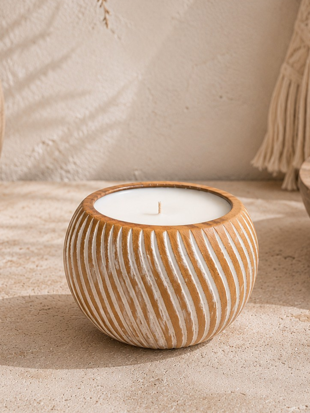 Grande bougie en bois massif sculpté avec rainures blanches et mèche centrale, présentée dans une décoration bohème minimaliste aux tons naturels.