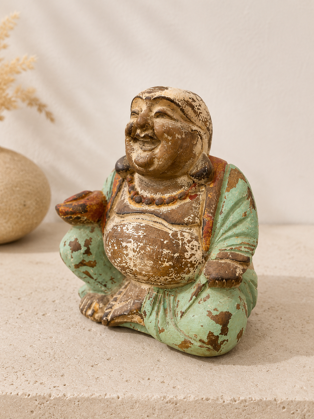 Vue de trois quarts du Bouddha rieur révélant sa patine ancienne.
