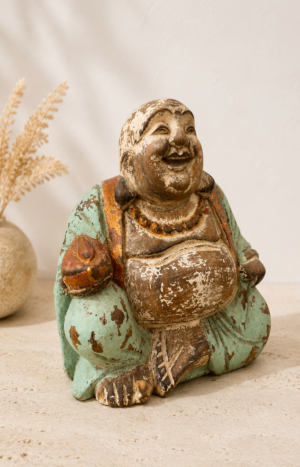 Bouddha rieur en bois massif patiné aux teintes vert d'eau et ivoire, présenté dans une ambiance galerie bohème chic.