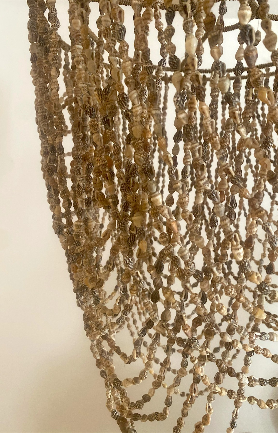 Détail des rangées de coquillages naturels assemblés à la main sur un lustre artisanal