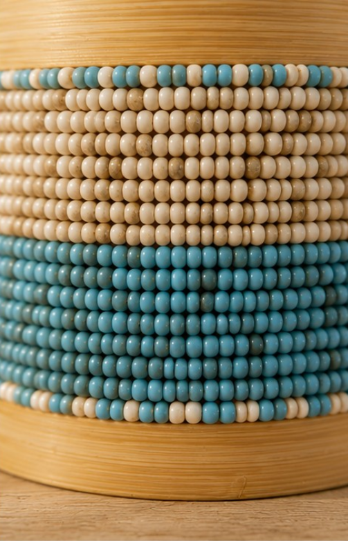 Gros plan sur les perles de verre bleu turquoise et beige d’une boîte artisanale en bambou.