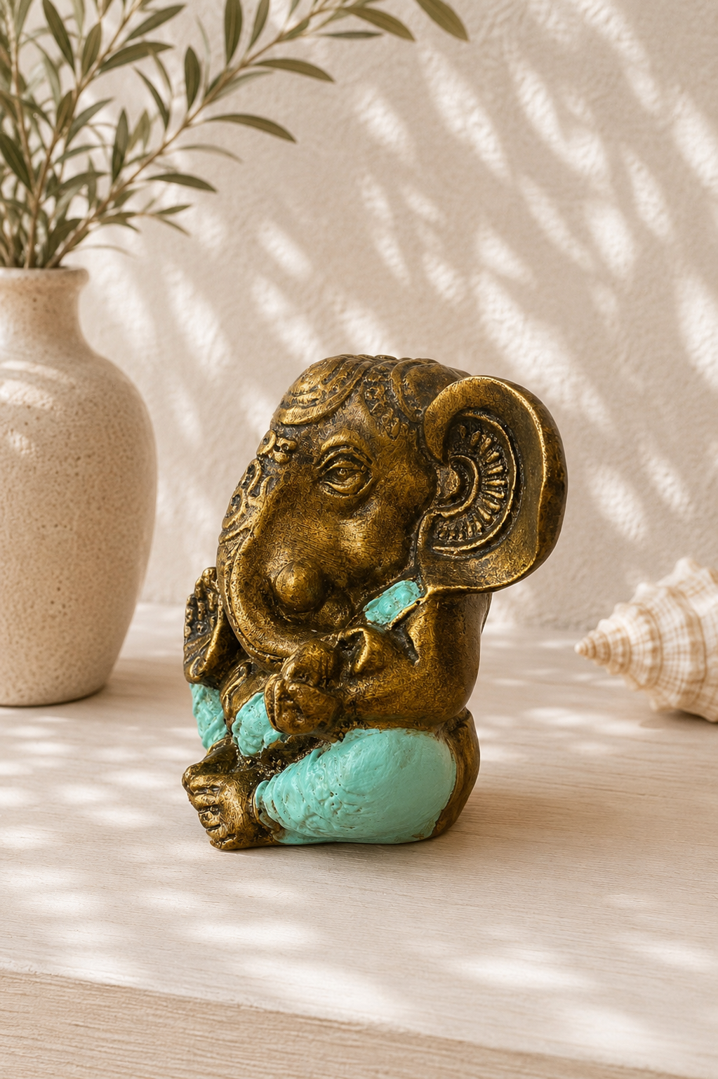 Vue de côté d'une statue Ganesh en résine turquoise finition dorée