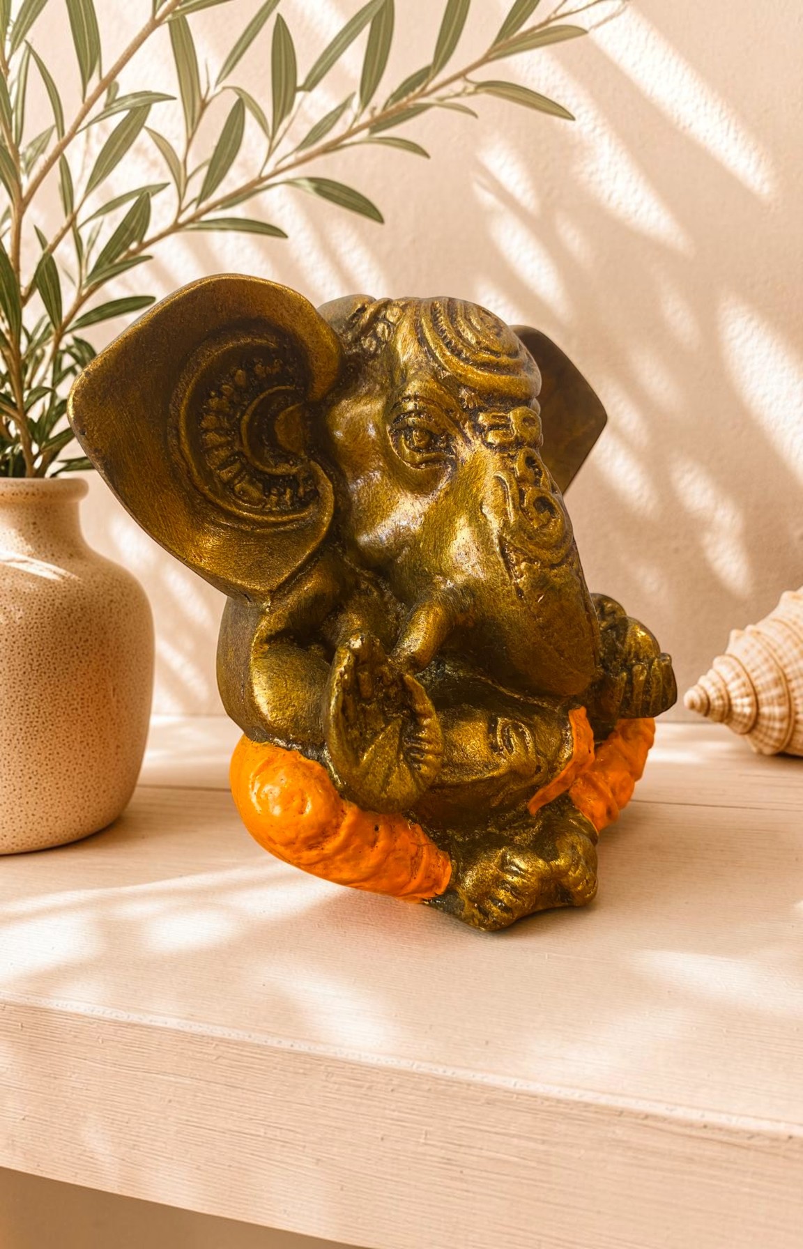 Vue de côté d'une statue Ganesh en résine orange finition dorée