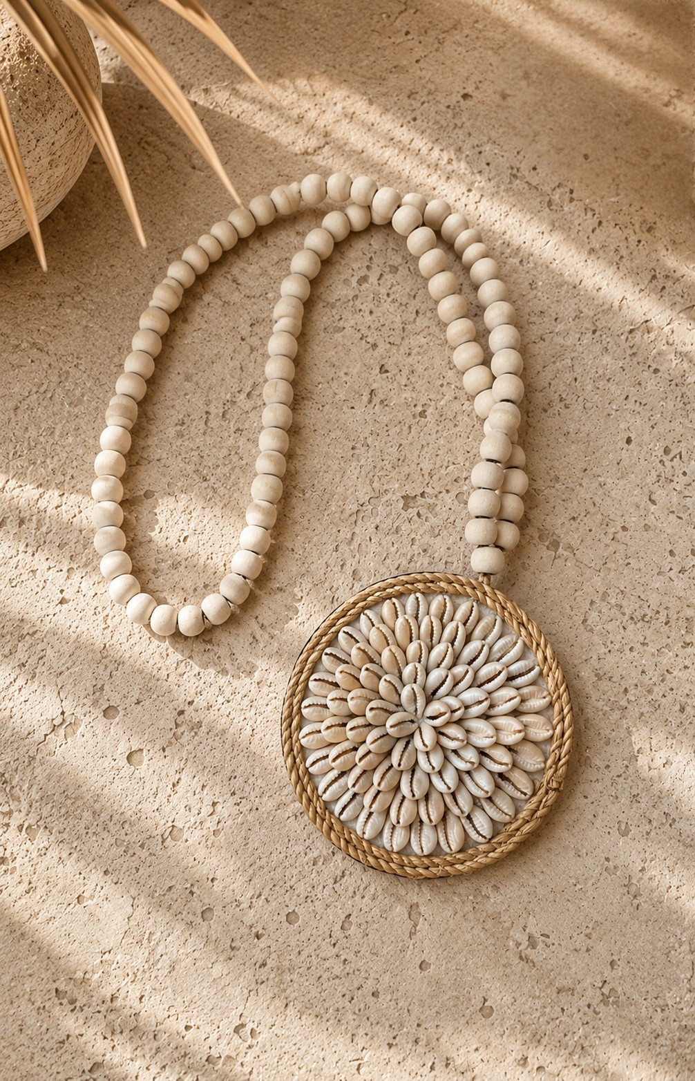 Médaillon décoratif en coquillages avec perles de bois, vue du dessus sur sol en pierre claire