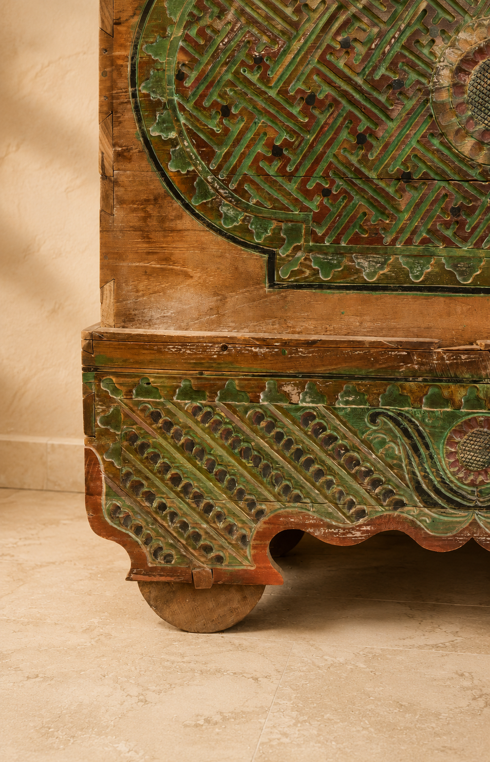 Détail des sculptures et des roulettes en bois d’un coffre ancien patiné