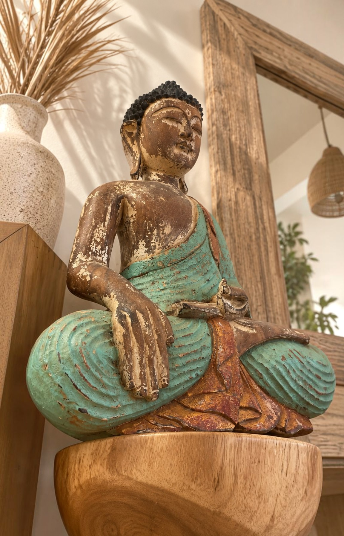 Bouddha assis en bois photographié en contre-plongée dans un décor naturel