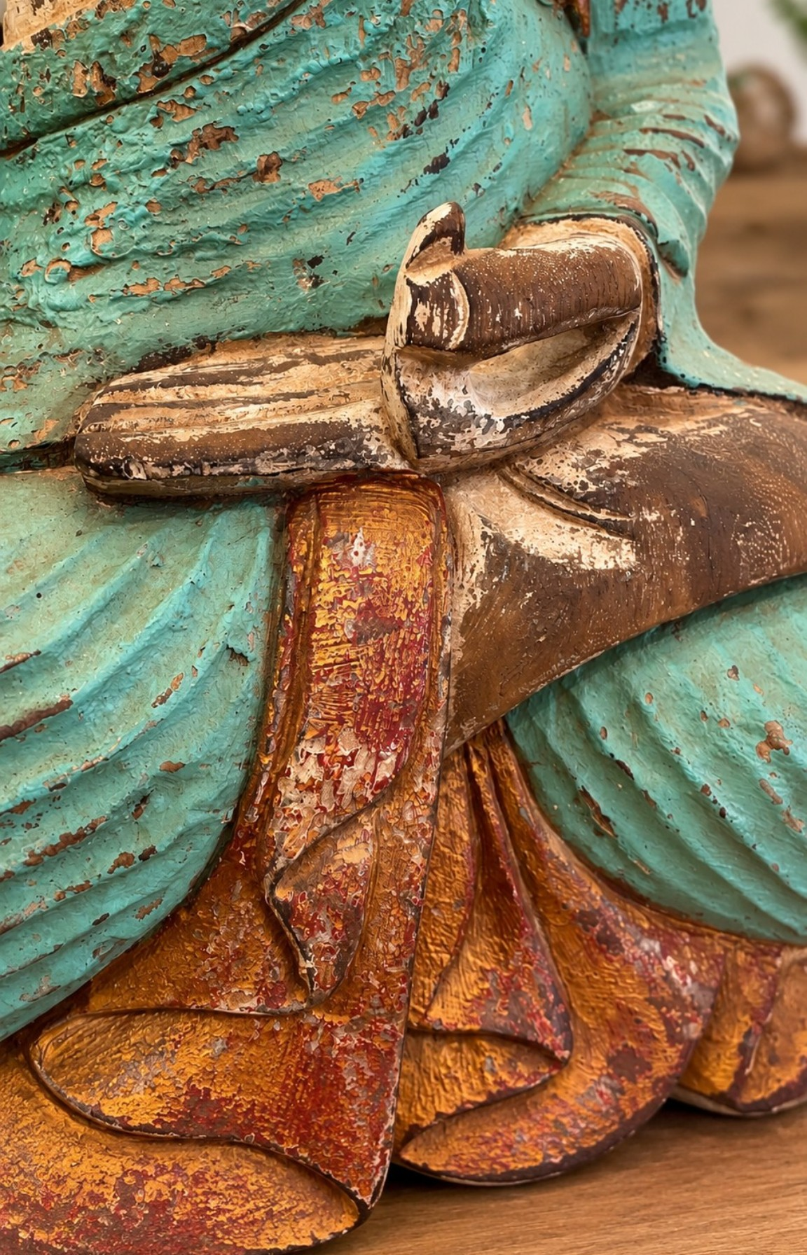 Détail de la main sculptée et de la patine turquoise d’une statue Bouddha