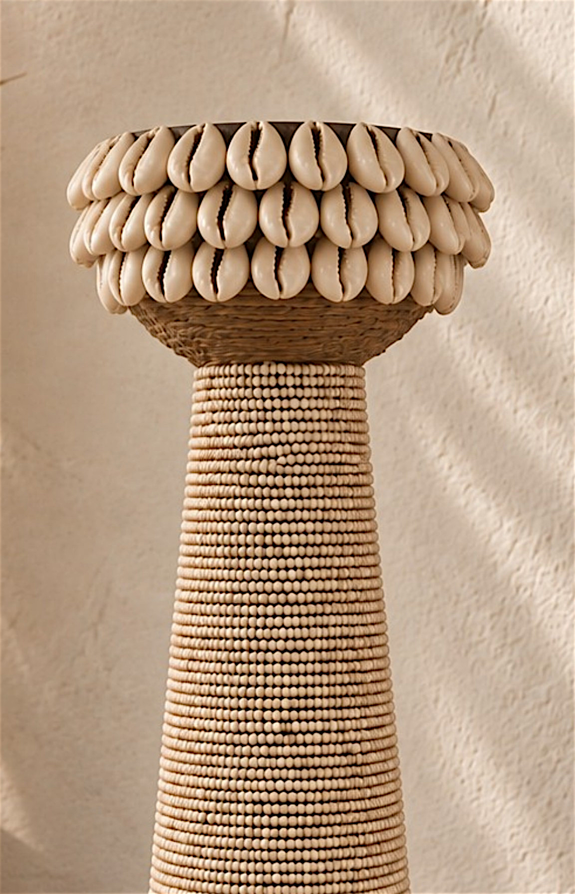 Détail des perles beiges, corde naturelle et coquillages sur un bougeoir décoratif