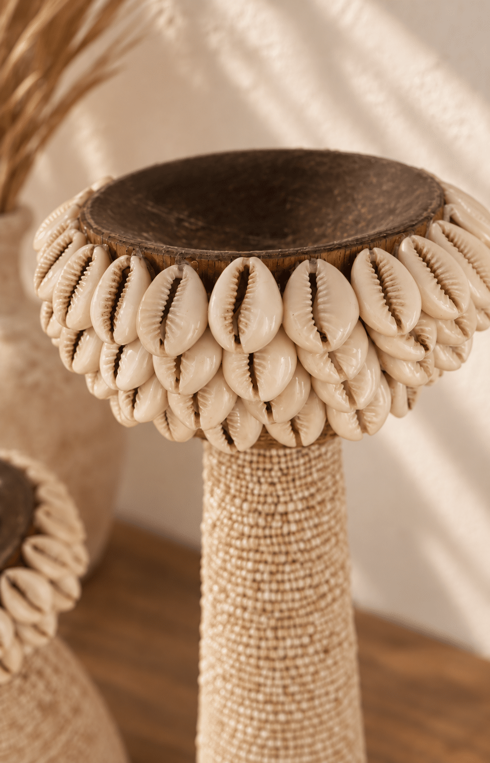 Gros plan sur les coquillages cauris d’un bougeoir bohème en bois et perles