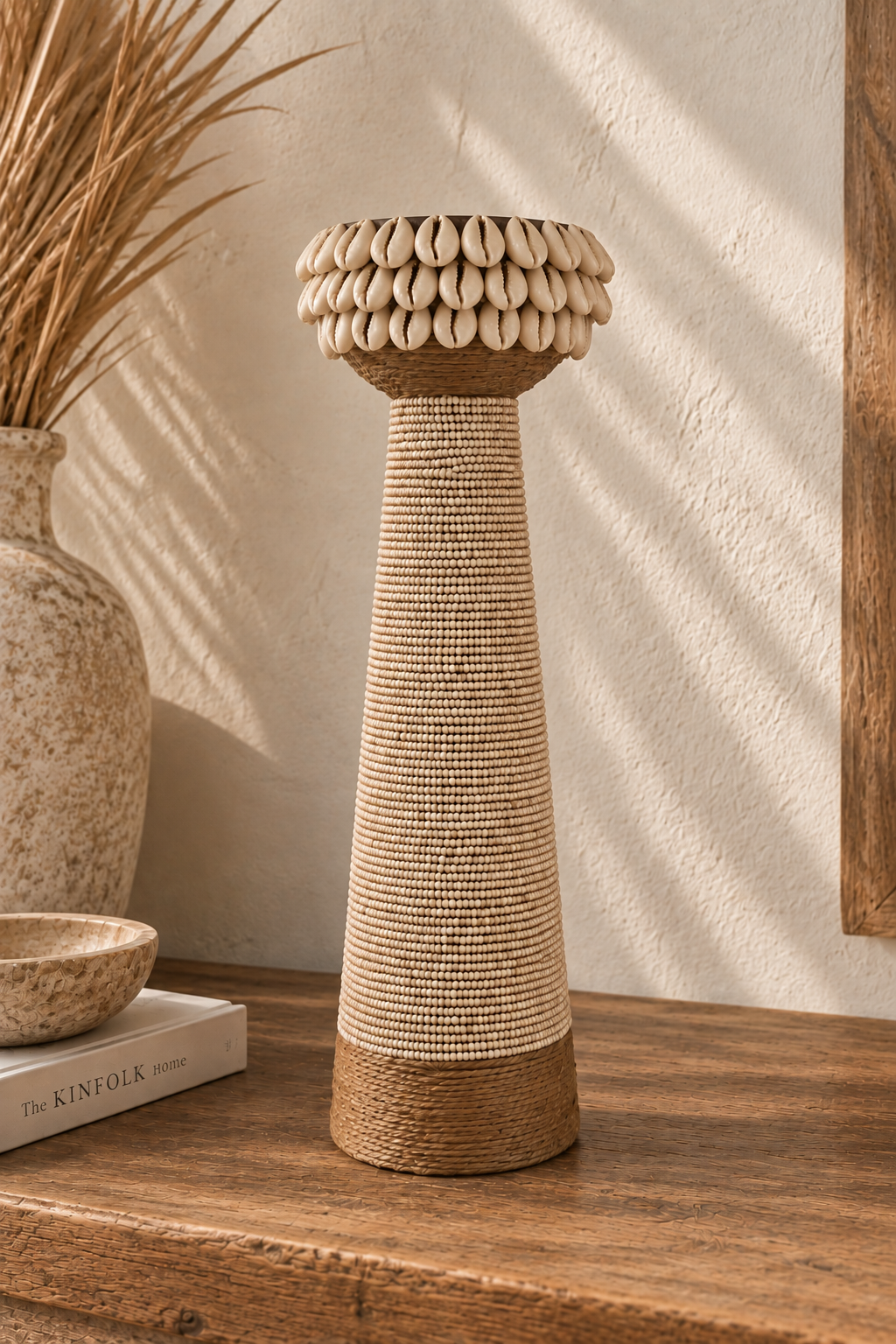 Grand bougeoir en bois avec perles beiges et coquillages cauris sur une étagère en bois brut