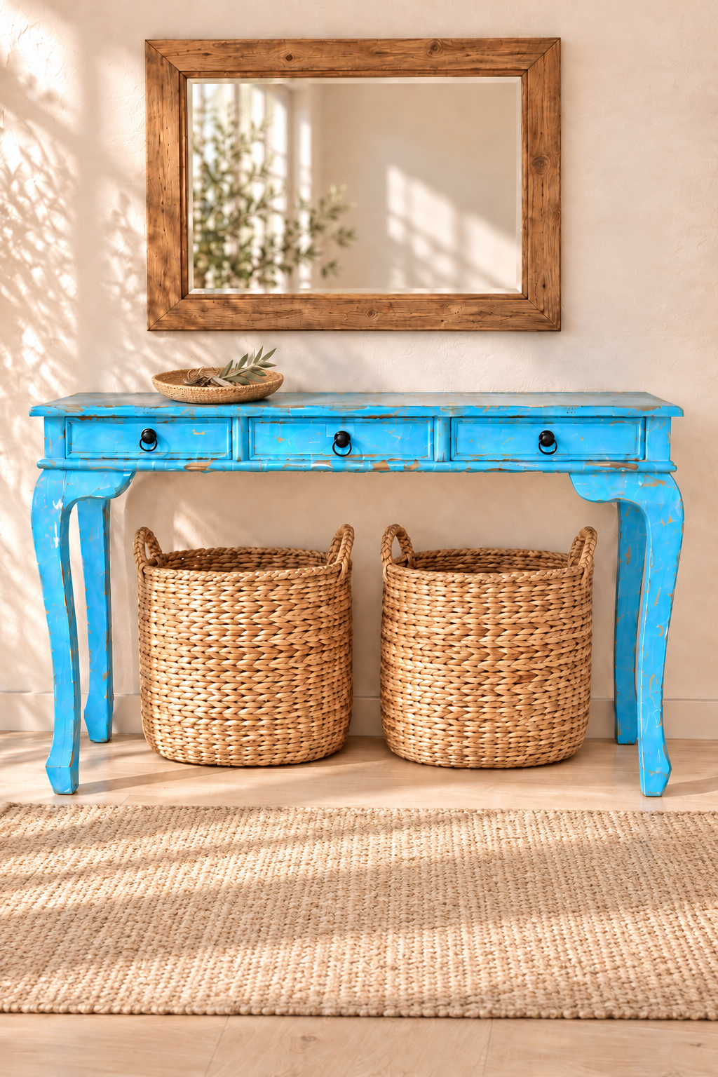 Console bleue patinée avec miroir rectangulaire en bois, paniers tressés et tapis naturel